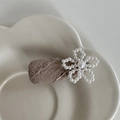 Dettaglio di un fermaglio per capelli in tessuto marrone con fiore di perle su vassoio ceramico - Marrone