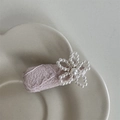 Dettaglio del fermaglio in pizzo rosa con fiore di perle su un piatto di ceramica - Rosa