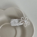 Dettaglio fermaglio per capelli con fiore di perle fatto a mano e pizzo su tessuto beige - Bianco