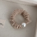 Dettaglio di un elegante elastico in organza beige con decorazione a perla grande - Albicocca