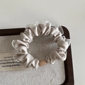 Detail of a beige silk scrunchie with silver lace edges and an oval pearl bead on wood - Mesh Edge Basic Loop - Apricot