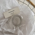 Detailansicht transparenter und rauchgrauer Spiralhaargummis in Papierverpackung - Off-White