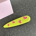Detailed view of lime green hair clip with three pink heart patterns on flat surface - Teardrop / Yellow-Green