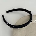 Dettaglio del cerchietto nero con perle bianche e borchie quadrate su piatto di ceramica - Nero