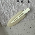 Macro view of cream matte hair clip on textured ceramic and handmade paper background - Milk White