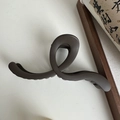 Macro shot of large wave matte brown claw clip showing elegant twisted cross structure - Matte Wave Deep Coffee