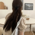 Detail of 3D satin black rose hair scrunchie styled on long hair in a cozy indoor setting - Black