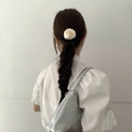 Detail view of a white satin rose scrunchie styled on elegant braided hair - White