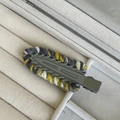 Close-up of knit-wrapped duckbill hair clip with grey, yellow, and white textures - Green