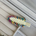 Dettaglio di fermaglio per capelli in lana intrecciata multicolore con clip in metallo - Bianco