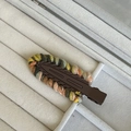 Detail of a handmade knitted hair clip with colorful wool edges on a gray velvet tray - Brown