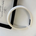 Close-up of a padded white velvet headband featuring a handmade fabric label inside - White