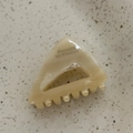 Dettaglio di una pinza per capelli triangolare in acetato con motivo marmorizzato e testo stampato - Bianco Sporco