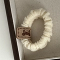 Détail d'un chouchou en maille avec étiquette ours en cuir et texture douce extensible - Blanc Cassé