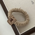 Detail view of khaki scrunchie with high elasticity and cute bear head leather patch - Apricot