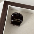 Macro-opname van een mini haarclip van acetaat met een gouden handgemaakte inscriptie - Zwart Koffie