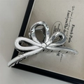 Macro detail of glossy silver metal hair claw clip featuring elegant hollow bow design - Ribbon Bowknot / Silver