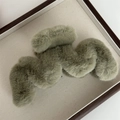 Détail d'une pince à cheveux en peluche vert sauge sur un plateau décoratif - Vert