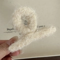 Dettaglio di una molletta per capelli in peluche beige con morbida consistenza in finta pelliccia - Piccola Forma a Gruccia / Crema