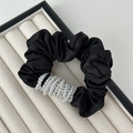 Dettaglio ravvicinato di un elastico in raso nero con eleganti decorazioni di perle bianche - Perla Bianca