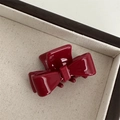 Detailed view of dark red acetate bow hair claw clip showing polished texture and teeth - Red