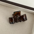 Macro shot of tortoiseshell acetate bow hair claw with glossy amber resin texture - Blue Coffee