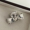 Detail of a creamy white bow hair claw clip with black marble ink pattern in a tray - Grey/White