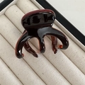 Close-up of tortoise shell pattern acetate hair claw clip on beige velvet interior - Red Brown