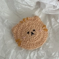 Detailed macro shot of an orange handmade crochet cat head hair clip on a paper background - Cat