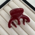 Gros plan sur une pince à cheveux rouge foncé brillante posée sur un plateau - Rouge