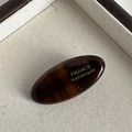 Macro detail of oval tortoiseshell hair clip showing France Handmade gold lettering - Dark Coffee