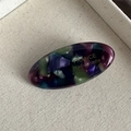 Detail of oval acetate hair clip with colorful resin patterns and golden France handmade text - Dark Multi-color