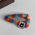Dettaglio di una molletta per capelli in maglia colorata con etichetta di orsetto - Fermaglio per capelli BB triangolare