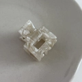 Macro view of square acetate hair claw clip with cream marble texture and metal spring detail - Beige Gray