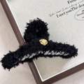 Dettaglio ravvicinato di una pinza per capelli in peluche nero con un emblema dorato a sorriso - Pinza per capelli / Black Smiley Face-Grab Clip