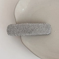 Nahaufnahme einer funkelnden rechteckigen Haarspange mit Mikro-Strass auf einer Keramikschale - Silberne Strass-Haarspange