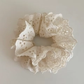 Macro detail of creamy white lace scrunchie with delicate embroidery and wavy edges - Off White