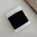 Close-up of five black ribbed seamless hair ties on a white display card with smiley icon - Black