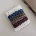 Detailed macro shot of four ribbed elastic hair ties in deep earth tones on a paper card - Multicolor