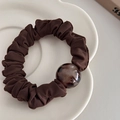 Detalle de un coletero fruncido marrón oscuro con una cuenta de resina de carey en un plato - café
