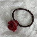 Dettaglio macro dell'elastico per capelli con rosa rossa in acetato lucido su lino - Rosso