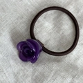 Dettaglio dell'elastico per capelli con rosa in resina viola su superficie di lino - Viola
