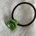 Dettaglio di un elastico per capelli con rosa verde su uno sfondo grigio testurizzato - Verde mela