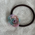Dettaglio dell'elastico rosa in resina a forma di rosa su tessuto di lino neutro - Blu e Rosa