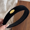 Close-up of black velvet padded headband featuring a gold oval handmade metal tag - Black Velvet Oval Gold Buckle - Wide Version
