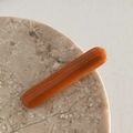 Makro-Detail einer bernsteinfarbenen Haarspange mit France Handmade Gravur auf Marmor - Orange