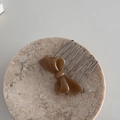 Close-up of brown acetate bow hair comb on a textured marble tray for daily styling - Light Coffee