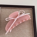 Detail of pink bow hair claw clip with satin ribbon on minimalist display base - Pink