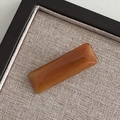Detailed macro of a rectangular amber acetate hair clip with gold France Handmade logo - Caramel color