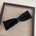 Elegant black bow hair clip with beaded edges and premium woven fabric on beige linen base - Black